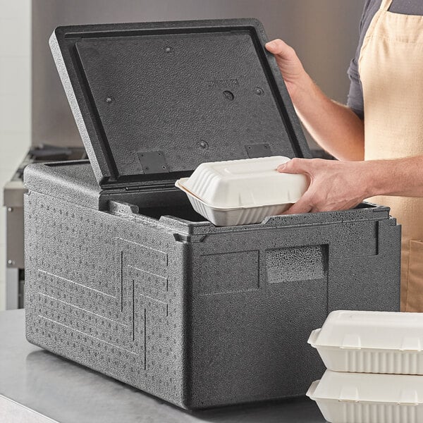 A person opening a Cambro black food pan carrier with a hand on top.