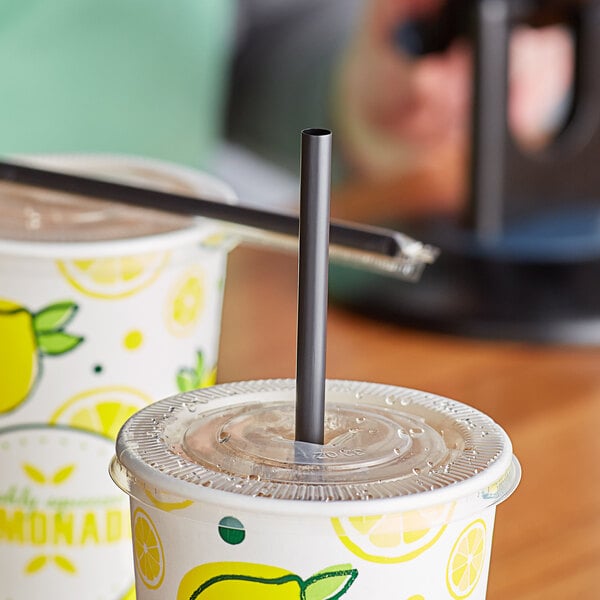 A table with two cups of lemonade, each with a black wrapped Choice Giant Straw in it.