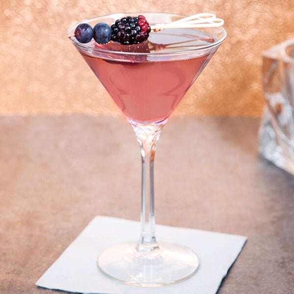 A Libbey martini glass with a drink and berries on the table.