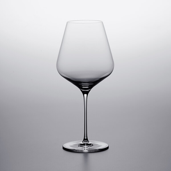 A Stolzle burgundy wine glass on a table with a white background.