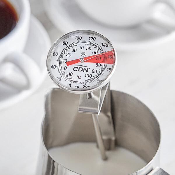 A CDN ProAccurate Insta-Read frothing thermometer in a metal container with white liquid.