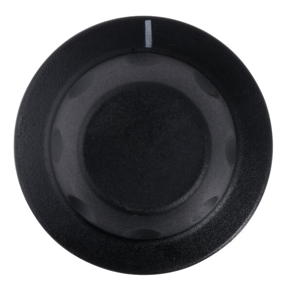 A close-up of a black round knob with a white line.