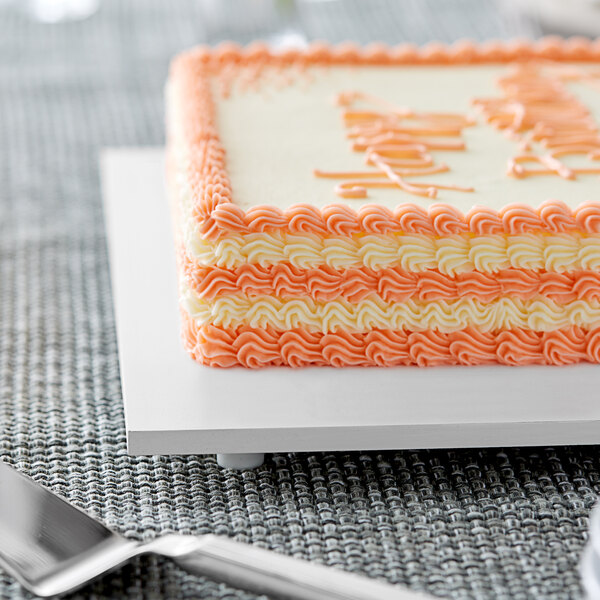 A close up of a cake on a white rectangular melamine-coated wood cake board with feet.