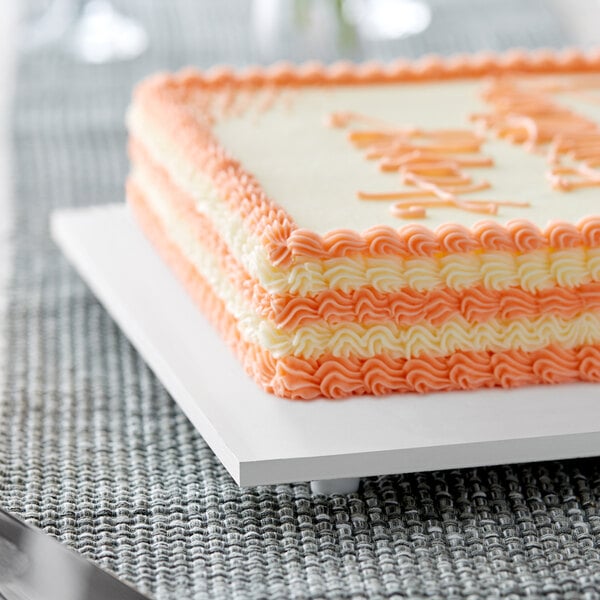 A white rectangular cake board with a cake on it.