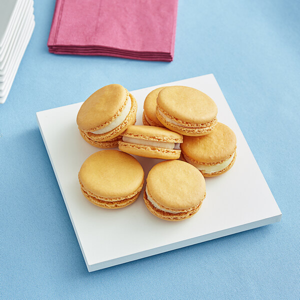 A group of cookies on a 6" x 6" white square melamine cake board.
