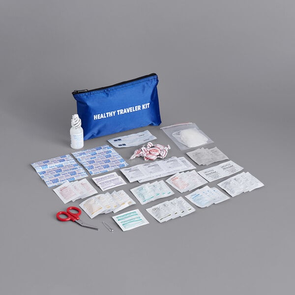 A blue Medique first aid kit with a red handled scissors and other items on a grey surface.