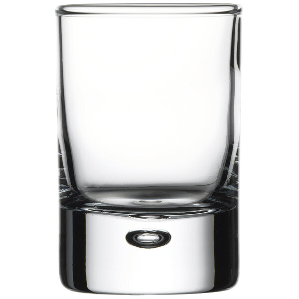 A close up of a Pasabahce clear shot glass with a small bubble.