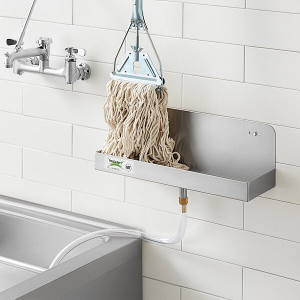 A Regency stainless steel mop sink drainage tray with a long metal hook and a broom.