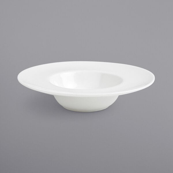 A Front of the House Monaco bright white wide rim porcelain saucer with a hole in the middle on a gray surface.