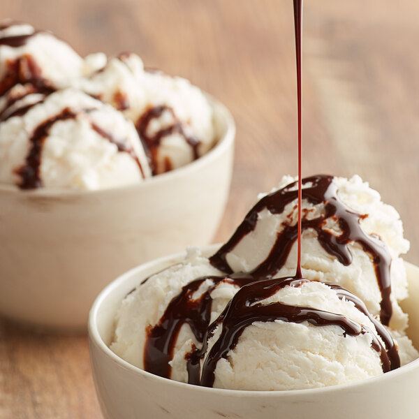 A bowl of ice cream with HERSHEY'S chocolate syrup on top.
