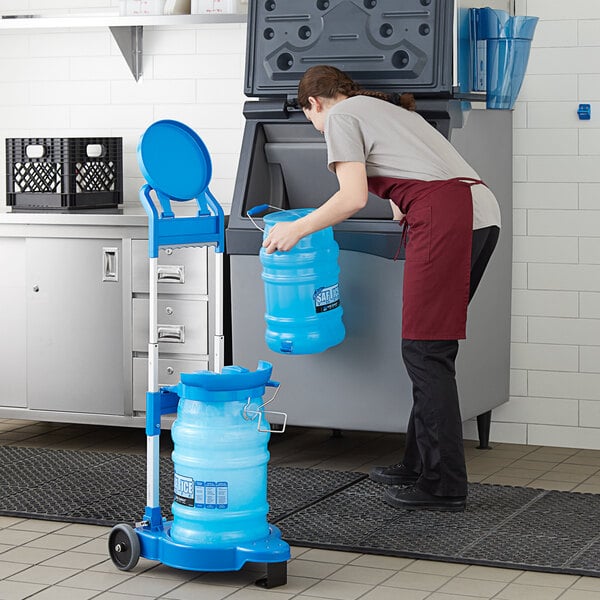 A woman using a San Jamar Saf-T-Ice ice tote to fill a large blue container with water.