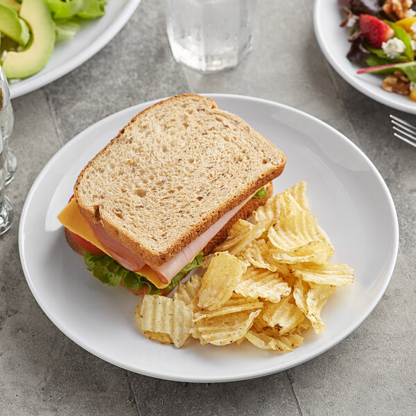 A plate of food with a sandwich and chips on an Acopa Lunar melamine plate.