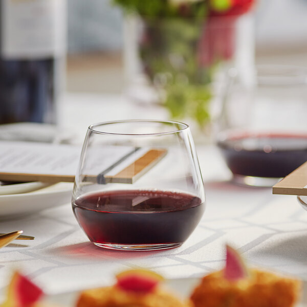 A stemless Acopa wine glass filled with red wine on a table.