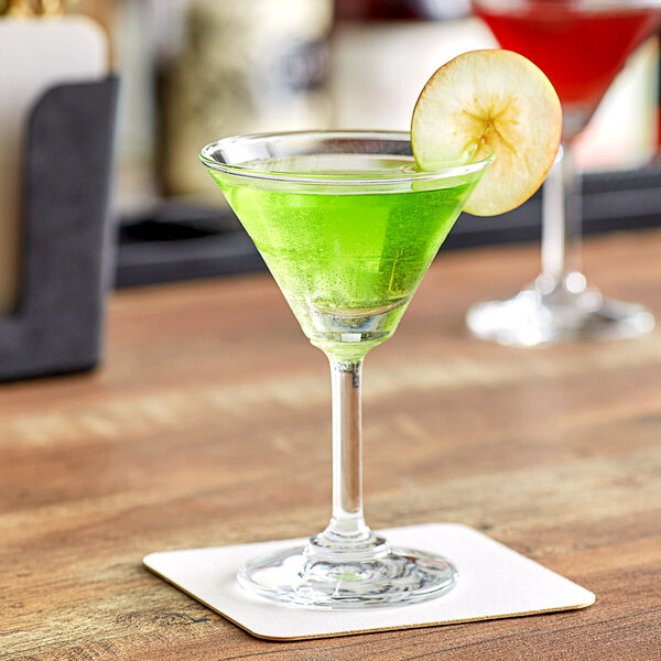 An Acopa Taster Martini glass with a green liquid and a slice of apple in it.