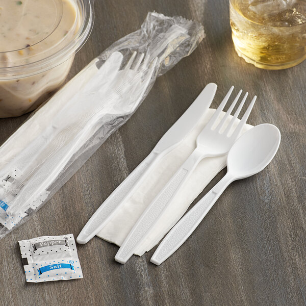 A white plastic Visions heavy weight cutlery pack with a napkin, salt and pepper packets.