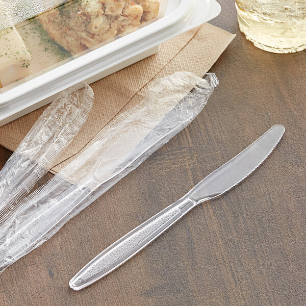 A plastic container with a plastic wrap around it and a Visions clear plastic knife