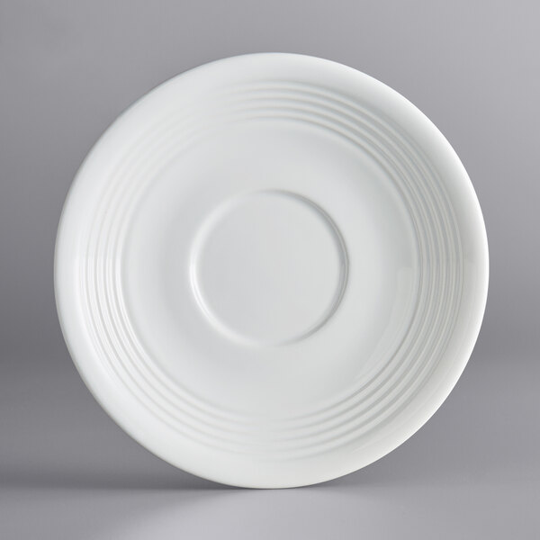 An Acopa Capri coconut white china saucer with a circular pattern on a white background.