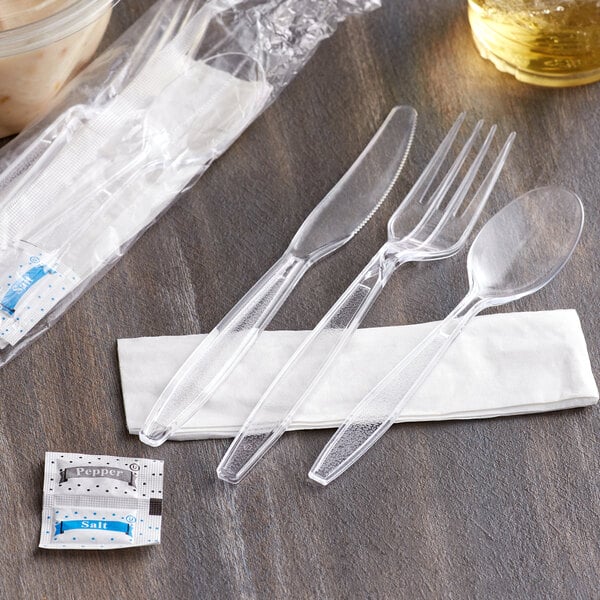 A clear plastic fork, knife, and spoon on a table.