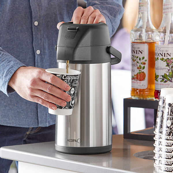 A person using an Acopa stainless steel decaf airpot to pour coffee into a cup.