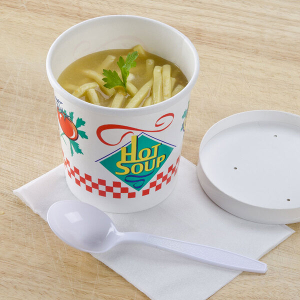 A Solo white paper soup cup with a plastic lid and a spoon on a white surface.