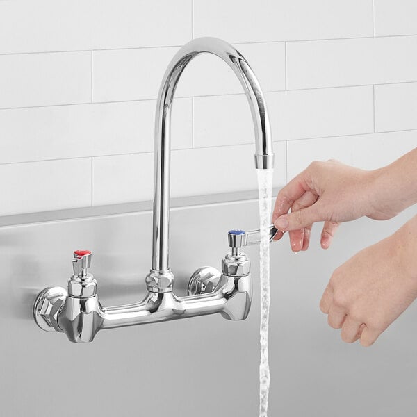 A person's hands opening a Waterloo wall mount faucet over a sink.
