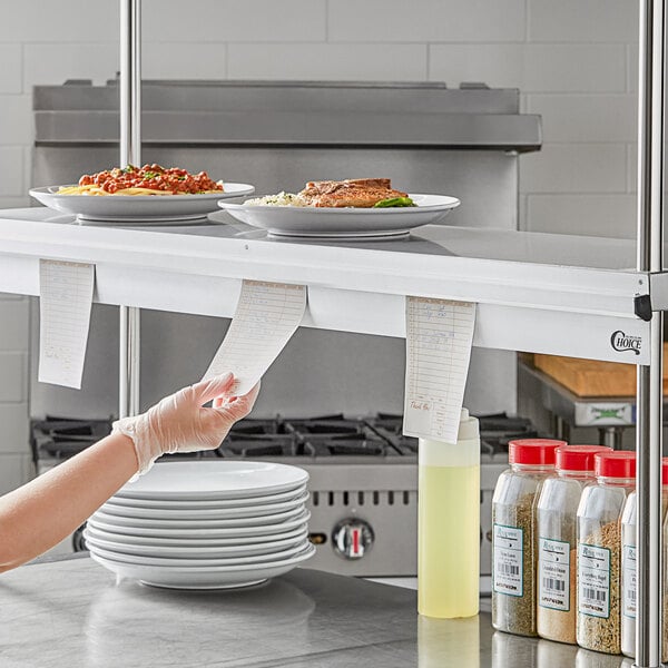 A Choice aluminum wall mounted ticket holder on a counter in a professional kitchen.