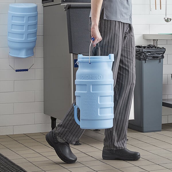 A man in a chef's outfit holding a large blue Vollrath Traex ice bucket.