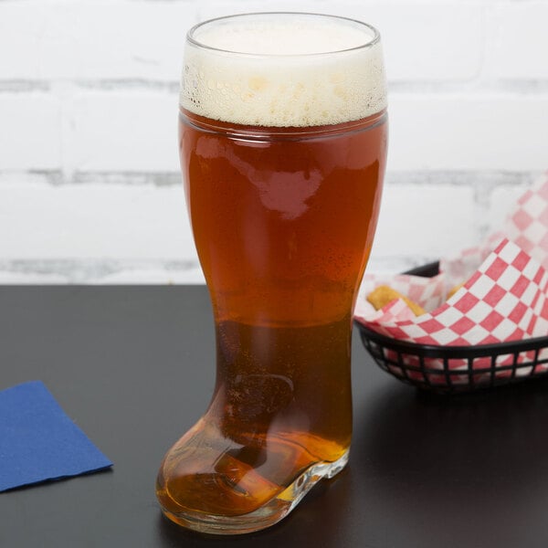 A Stolzle beer boot glass filled with beer on a table.