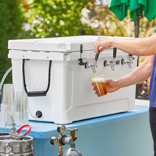 A man pouring a beer from a tap into a CaterGator white insulated cooler.