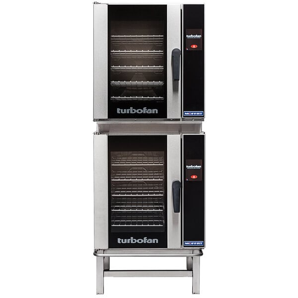 A close-up of two large black and silver Moffat Turbofan double deck electric convection ovens.