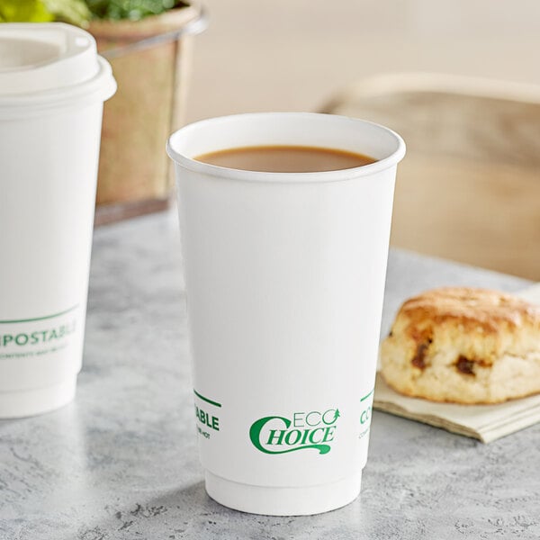 A table with a white EcoChoice paper cup of coffee and a biscuit.