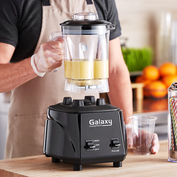 A man using a Galaxy commercial blender on a counter to make a smoothie.
