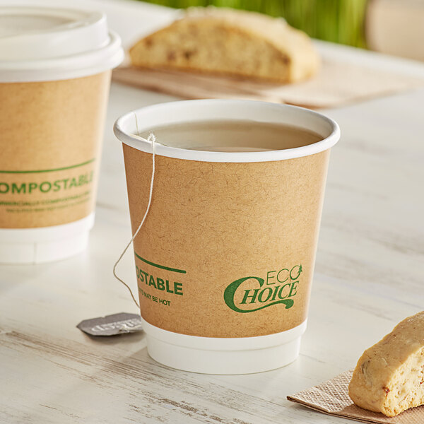 Two EcoChoice double wall paper hot cups filled with tea on a table with a biscuit.