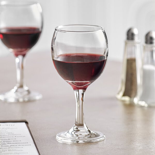 Two Acopa all-purpose wine glasses filled with red wine on a table.