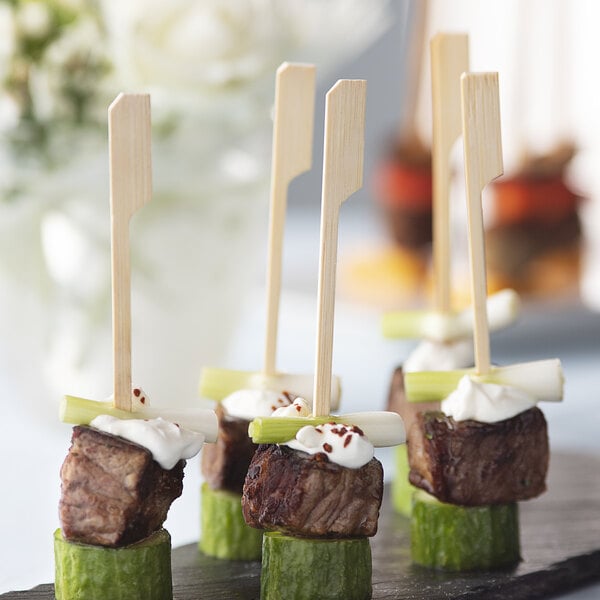 A piece of meat and a green vegetable on a bamboo skewer.