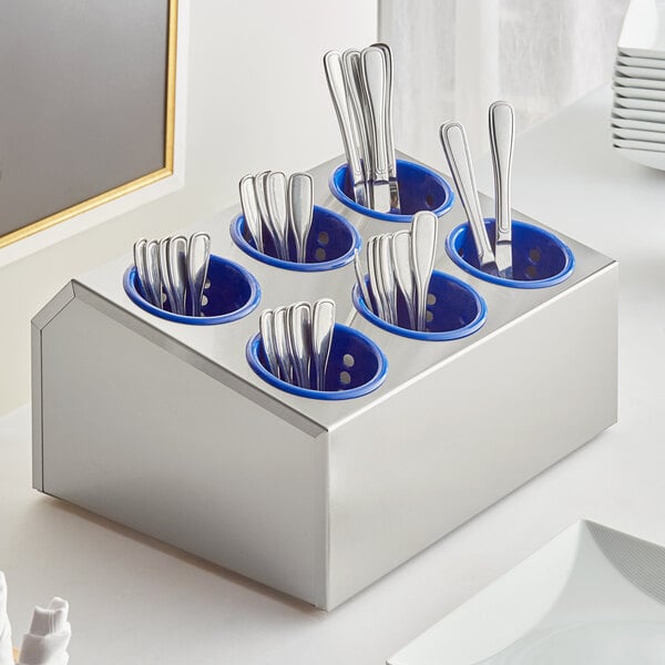 A Choice stainless steel flatware organizer with blue plastic cylinders holding silverware.