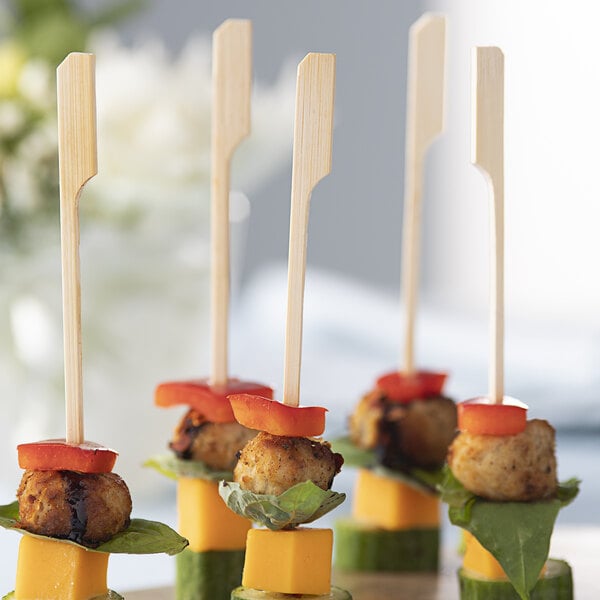 A plate of food on Bamboo by EcoChoice skewers on a table at a catering event.