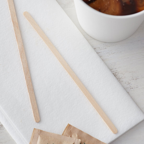 A cup of tea with a Choice wooden coffee stirrer on a white surface.