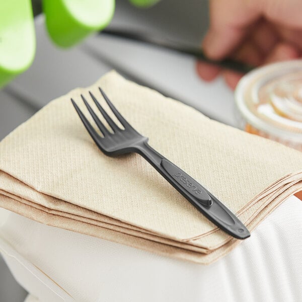 A black plastic fork on a white napkin.