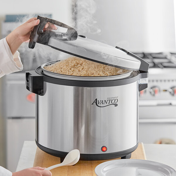 A woman using an Avantco electric rice warmer to cook rice.