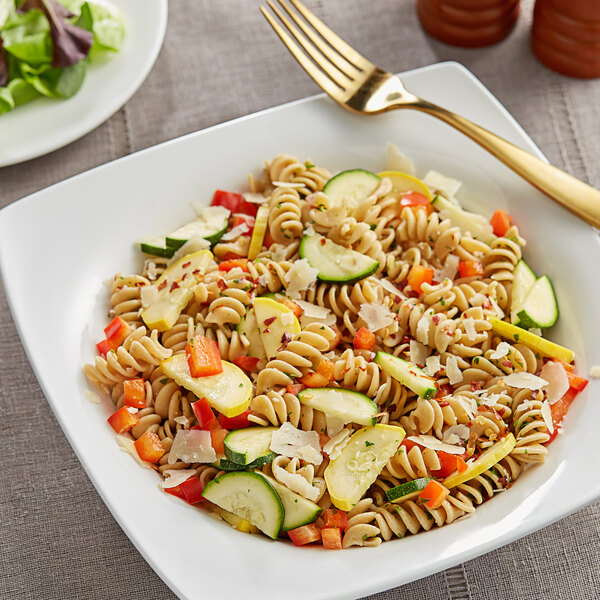 A plate of Barilla whole grain rotini pasta salad with vegetables and a fork.