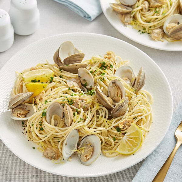 A plate of Barilla spaghetti with clams and lemon slices.