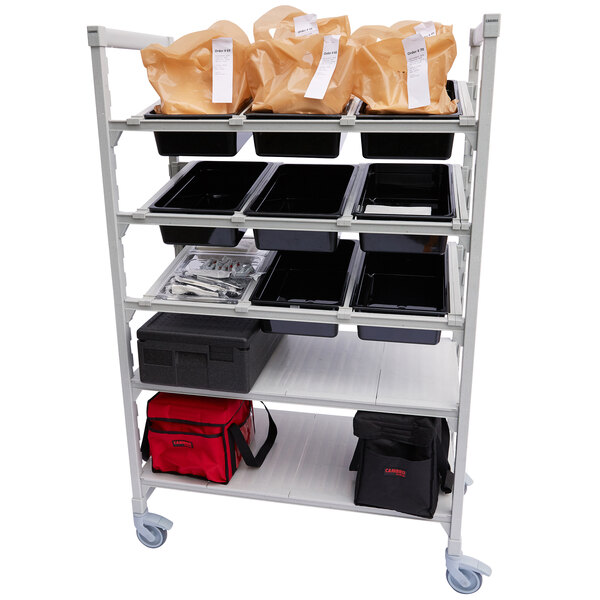 A white Cambro Camshelving Premium Flex Station with plastic trays and bags on shelves.