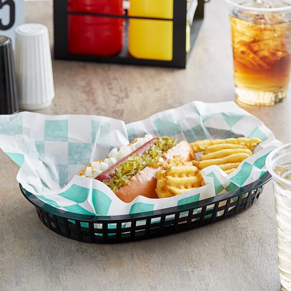 A Choice green check basket liner with a hot dog and fries in a basket.