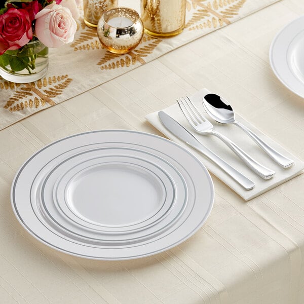 A white table setting with Visions silver banded plastic plates and classic flatware.