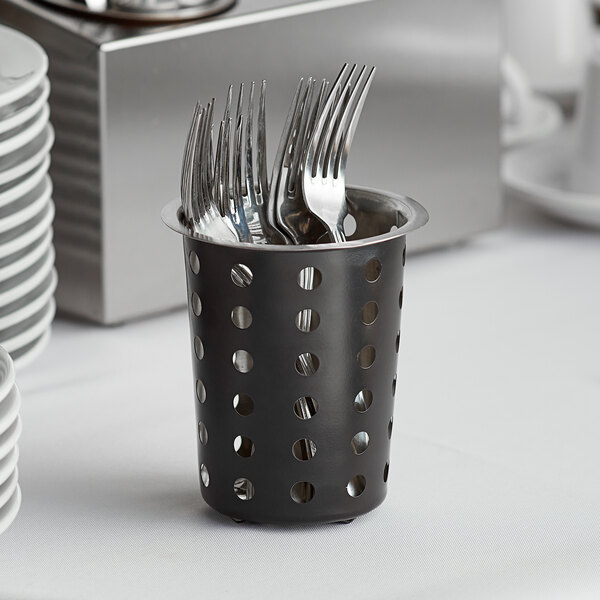 A matte black metal cylinder with holes holding silverware.