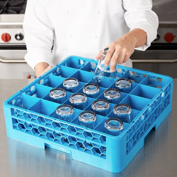 A person putting clear glasses into a Carlisle glass rack with blue extenders.