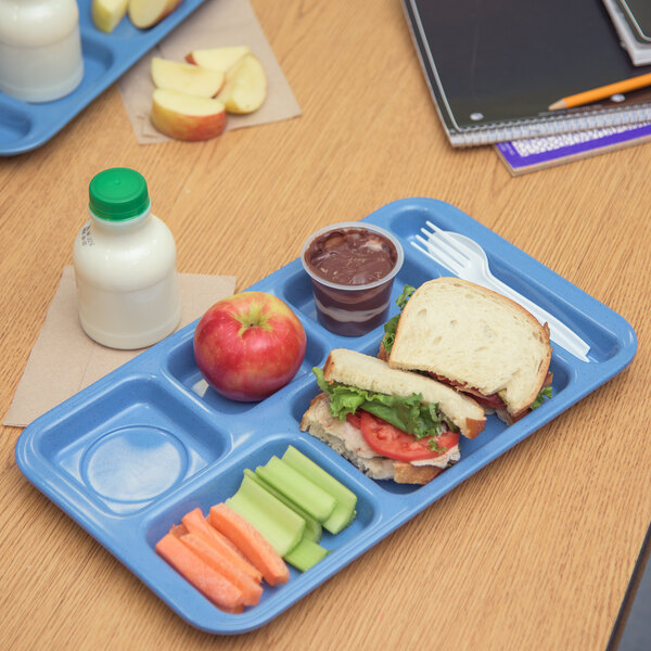 A Carlisle sandshades tray with a sandwich, apple, and juice on a school lunch tray.