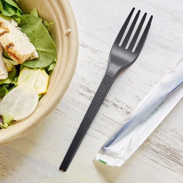 A bowl of salad with a black EcoChoice wrapped plastic fork.
