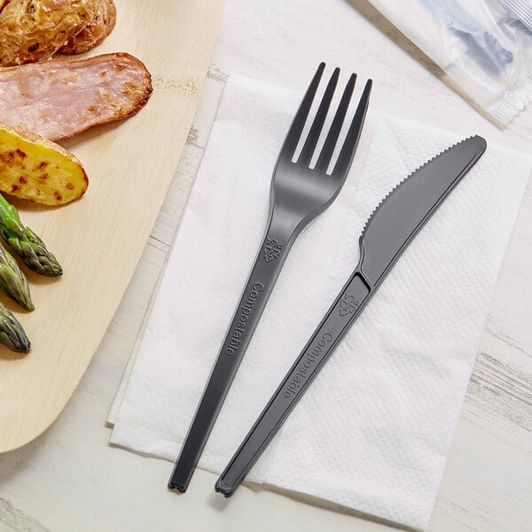 A black EcoChoice CPLA fork and knife on a white napkin.